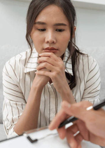 Young woman thinking with folded hands beneath her chin during a discussion about medication-assisted treatment for cocaine use disorder