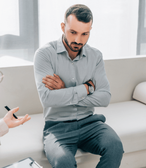 A man with crossed arms listening as a therapists explains drug addiction treatment programs